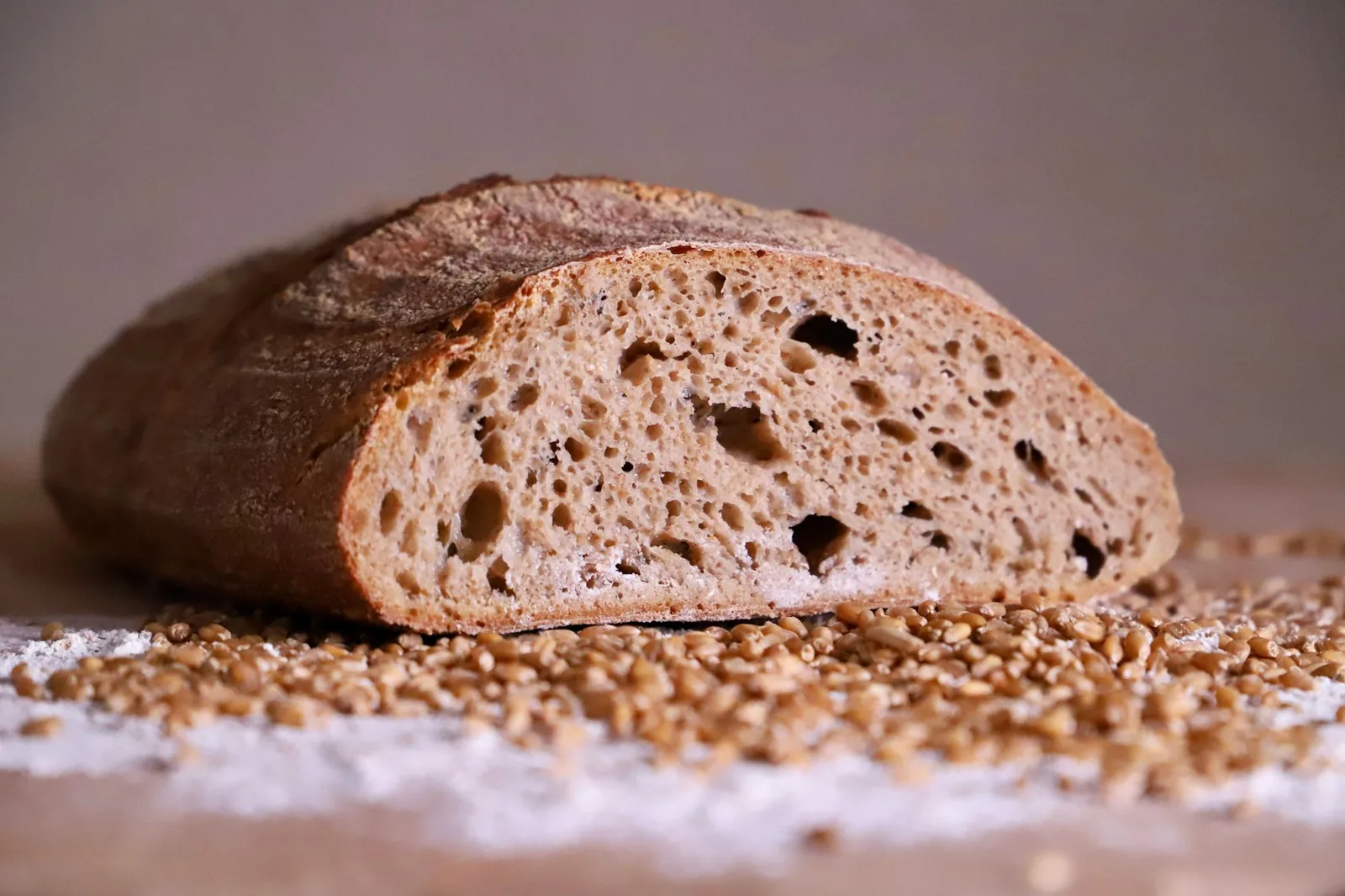 Vekna hleba i klasje pšenice na drvenom stolu — ilustracija glutena i celijakije