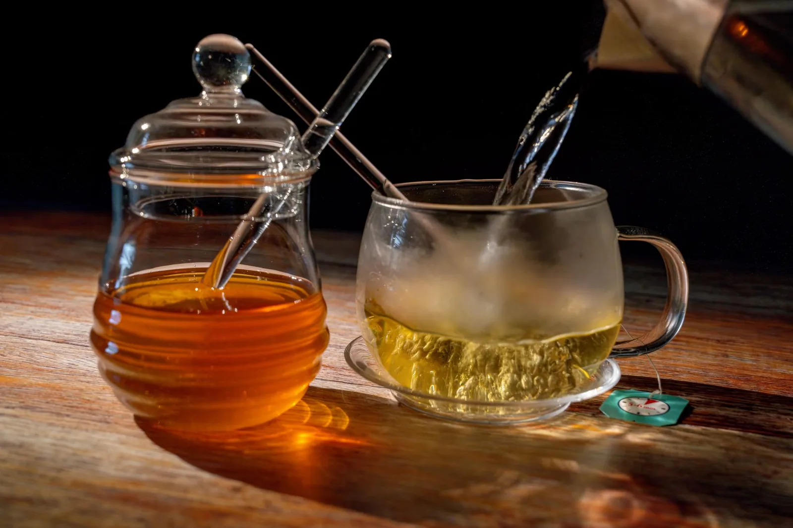 Teglica manuka meda sa drvenom kašikom i saćem na svetloj podlozi